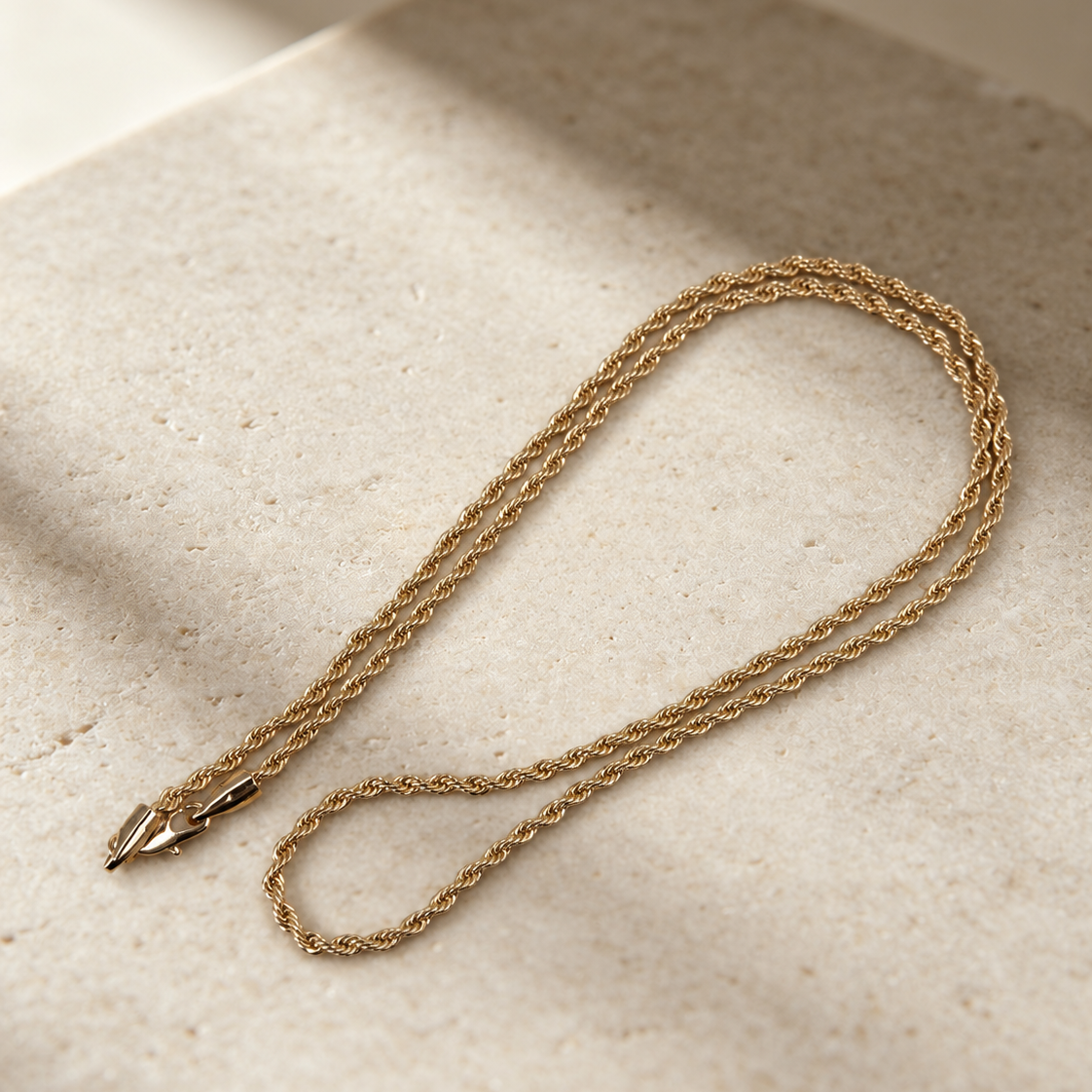 Corda 14K gold-plated steel rope chain necklace in an elongated loop, showing its twisted texture and lobster clasp.