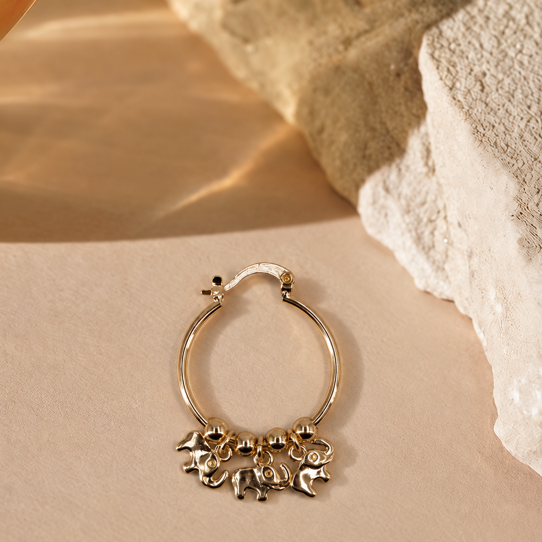 Nila 14K gold-plated steel hoop earring with three dangling elephant charms and polished round beads along the bottom.