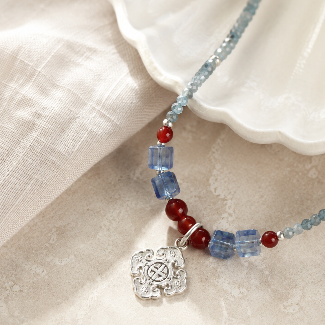 Close-up of sky blue quartz beads, red accents, sterling silver spacer beads, and sterling silver pendant in Azure Sky Blue Quartz Pendant Necklace