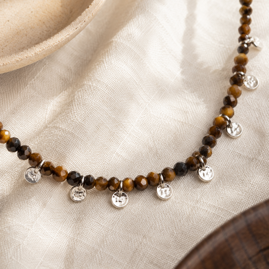 Close-up of faceted tiger’s eye beads and sterling silver charm accents in Aurelia Tiger’s Eye Sterling Silver Charm Necklace
