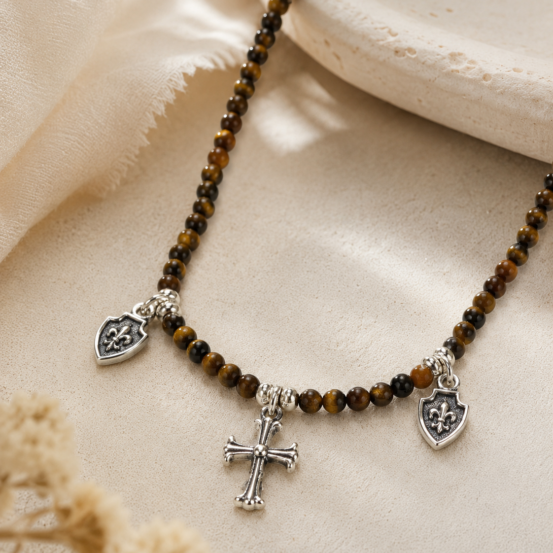 Close-up of tiger’s eye beads, sterling silver cross charm, and shield charms in Tiger’s Eye Cross Charm Beaded Necklace