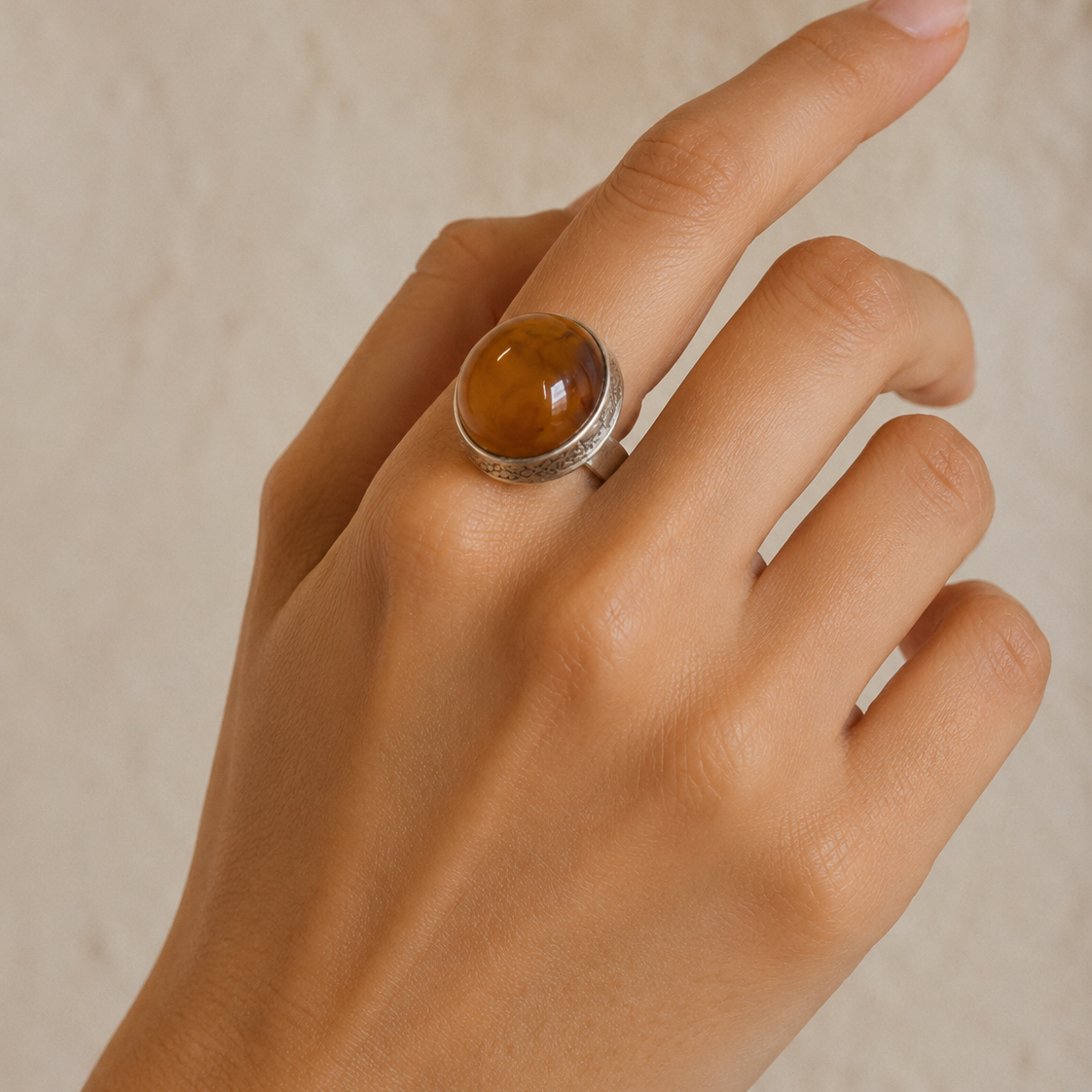 Close-up of polished golden-brown amber and sculptural sterling silver setting in Golden Amber Sterling Silver Adjustable Ring