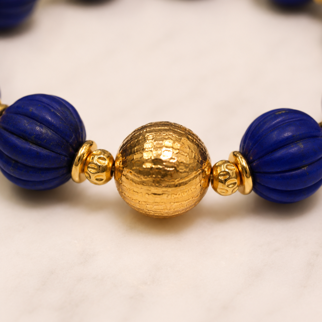 Close-up of carved lapis lazuli beads and gold-plated sterling silver detail in Lapis Lazuli Gold Beaded Statement Bracelet
