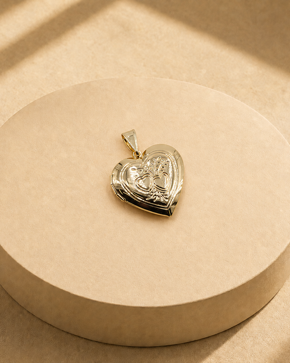 Adora gold-plated heart pendant with two outlined hearts and leafy sprigs on a cream display.