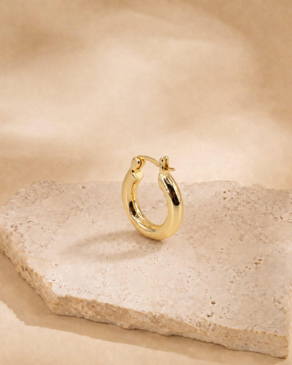 Alba classic hoop earring at an angle, showing the curved polished surface and hinged post fastening.
