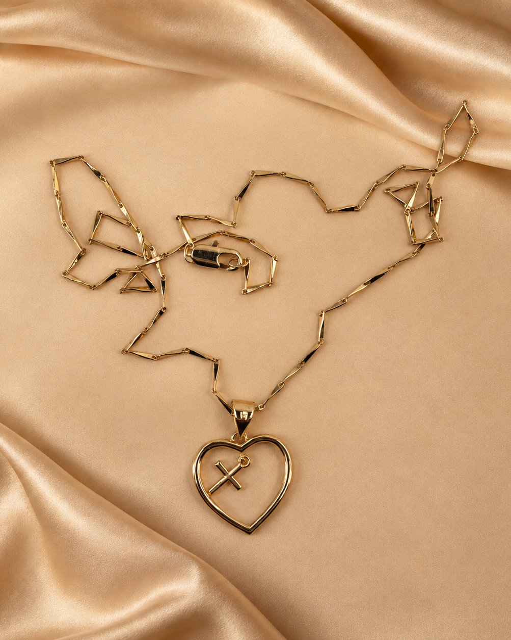 Front detail of the Amara open-heart pendant with a small hanging cross, alongside its 14K gold-plated chain and lobster clasp.