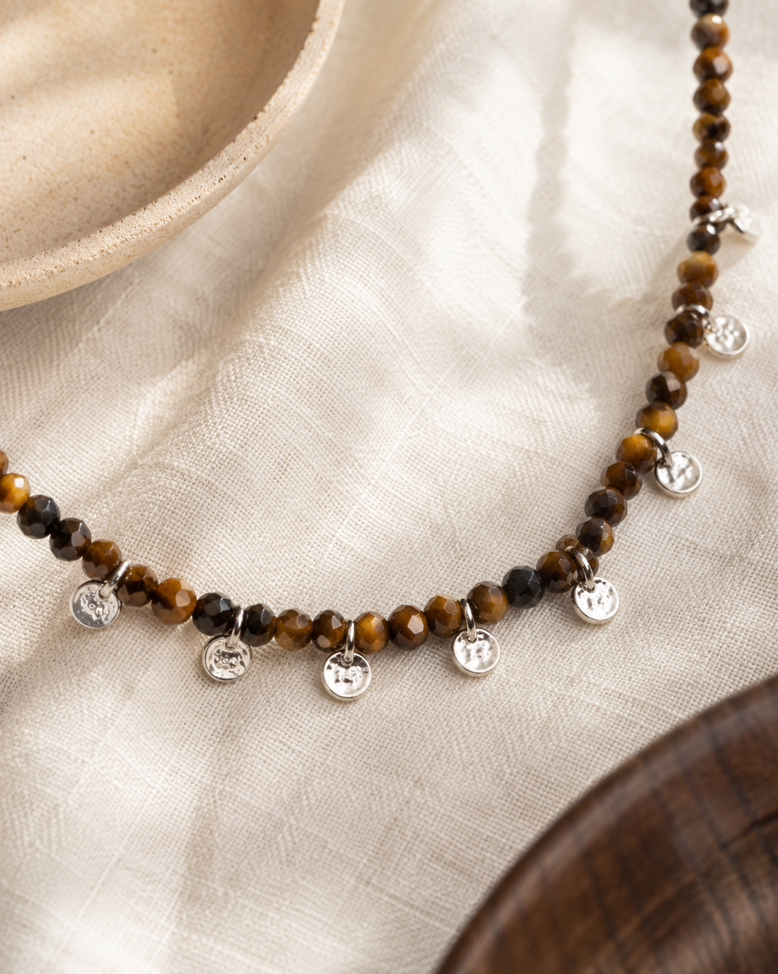 Close-up of faceted tiger’s eye beads and sterling silver charm accents in Aurelia Tiger’s Eye Sterling Silver Charm Necklace