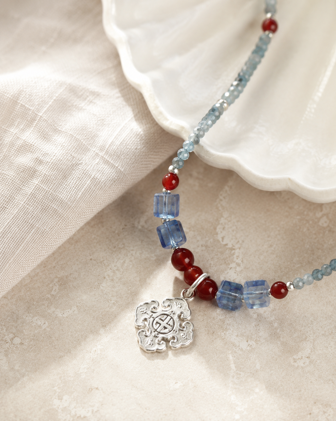 Close-up of sky blue quartz beads, red accents, sterling silver spacer beads, and sterling silver pendant in Azure Sky Blue Quartz Pendant Necklace