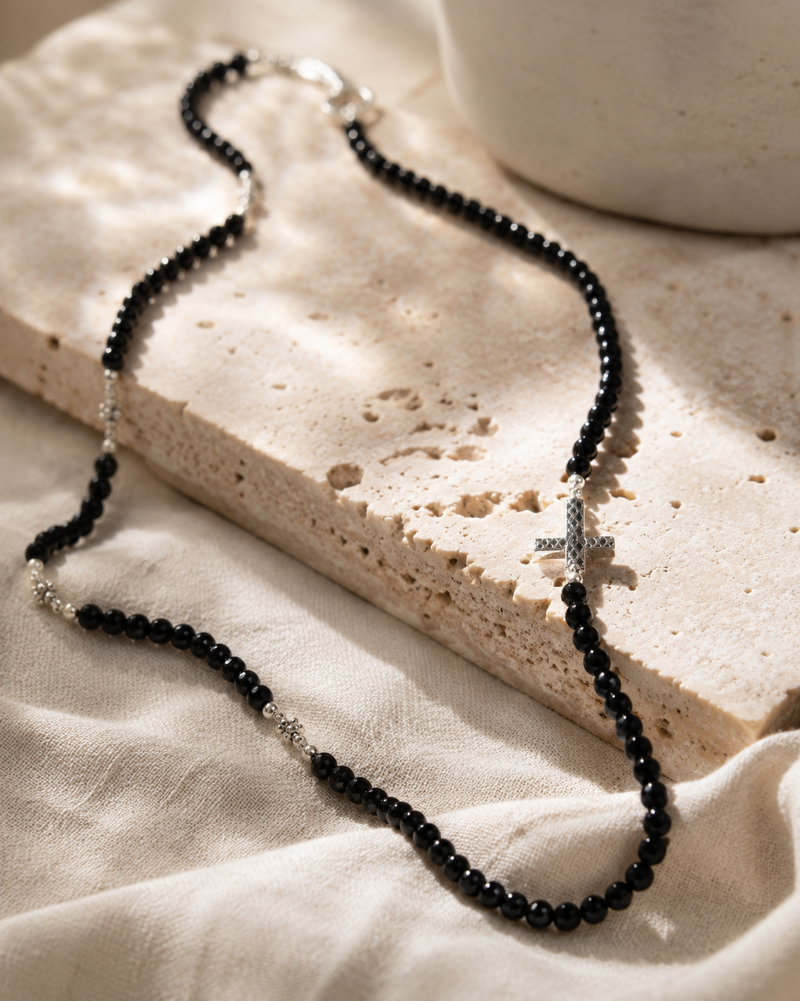 Close-up of polished black spinel beads and textured sterling silver cross accent in Black Spinel Sterling Silver Cross Necklace