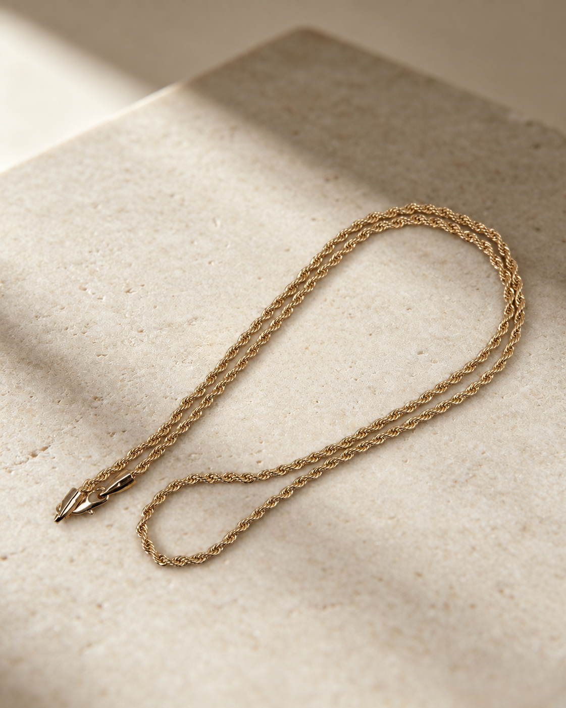Corda 14K gold-plated steel rope chain necklace in an elongated loop, showing its twisted texture and lobster clasp.