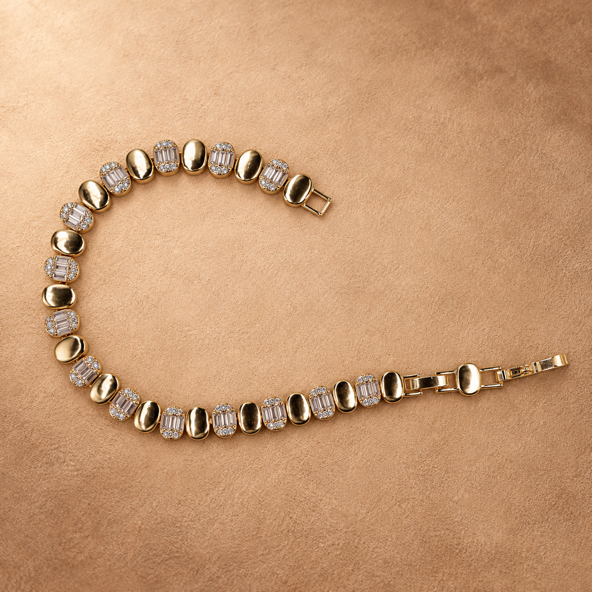Dalia oval link bracelet laid in an open curve, showing the clasp, polished gold finish and clear rectangular accents.
