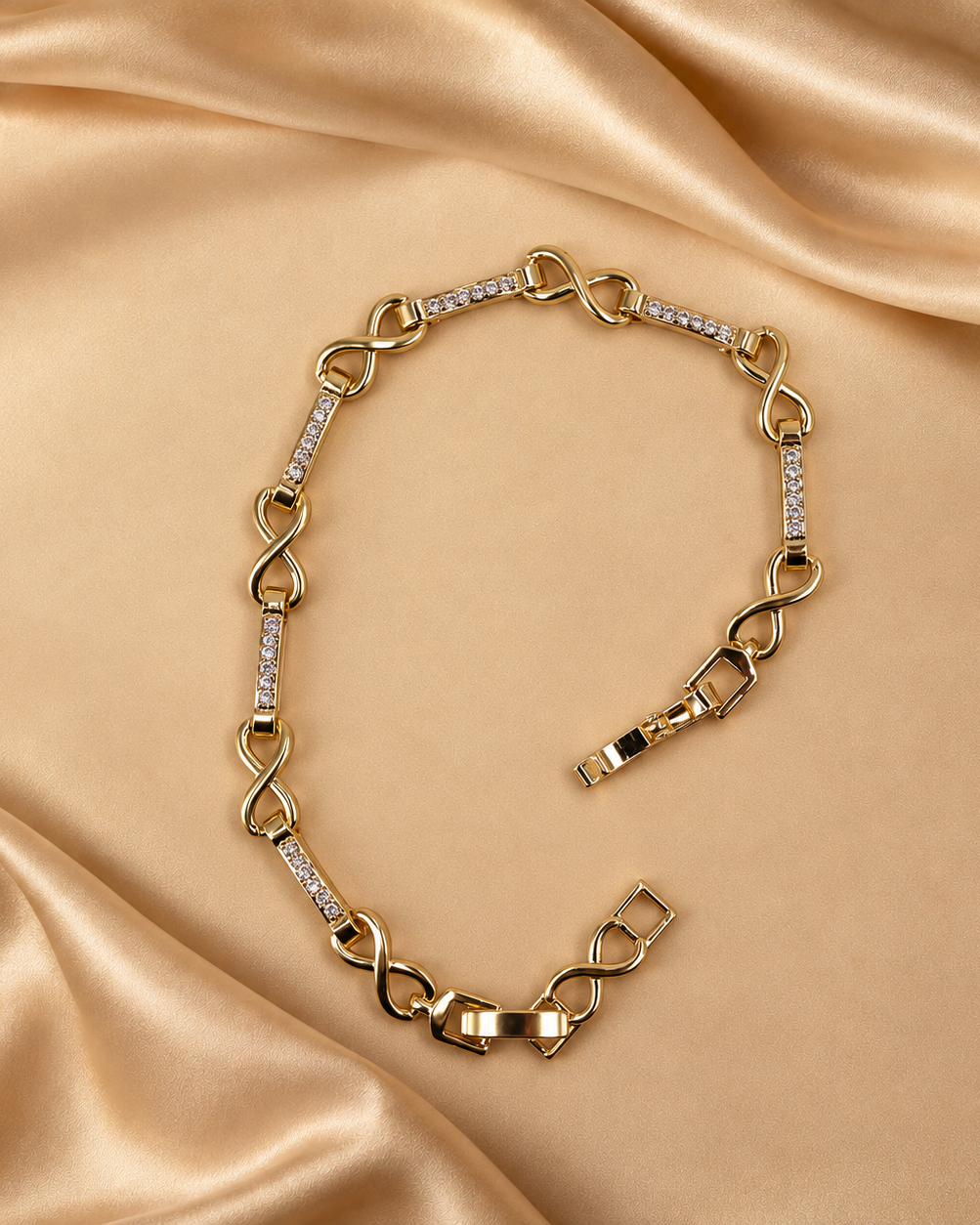 Evera 14K gold-plated steel bracelet laid open, showing infinity-shaped links alternating with bars of clear accents.