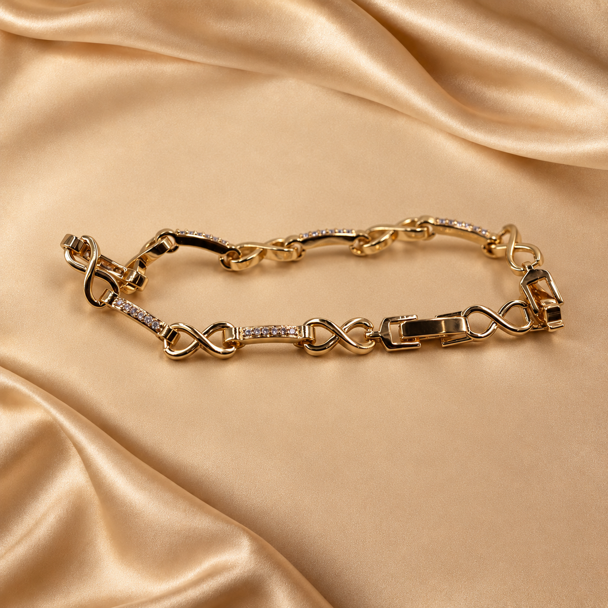 Low angled view of Evera gold-plated bracelet, highlighting curved infinity links, accented bars and the fold-over clasp.