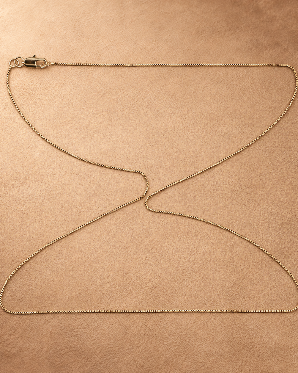 Linea 14K gold-plated steel box chain necklace arranged in a broad loop, showing its fine square links and lobster clasp.