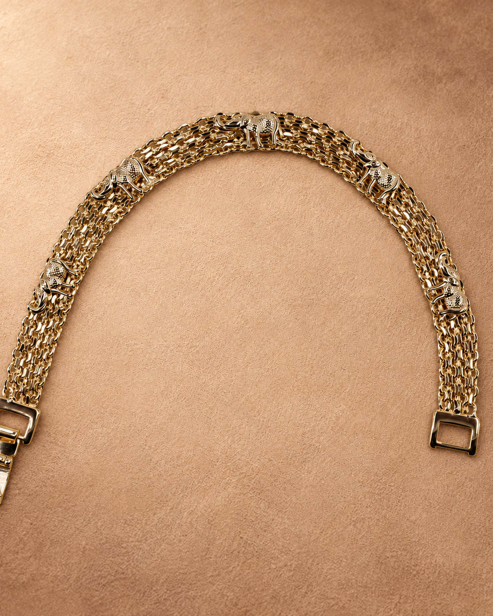 Nila 14K gold-plated elephant bracelet arranged in an open curve, showing textured elephant motifs, multiple chain rows and a fold-over clasp.