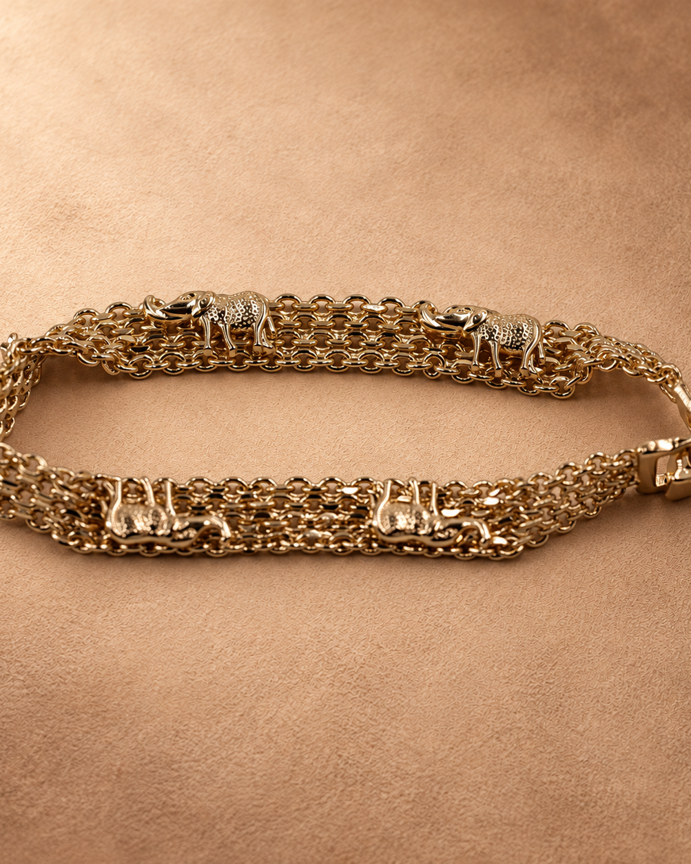Angled close-up of the Nila elephant chain bracelet with its clasp closed, showing the raised elephant details and layered gold-plated links.