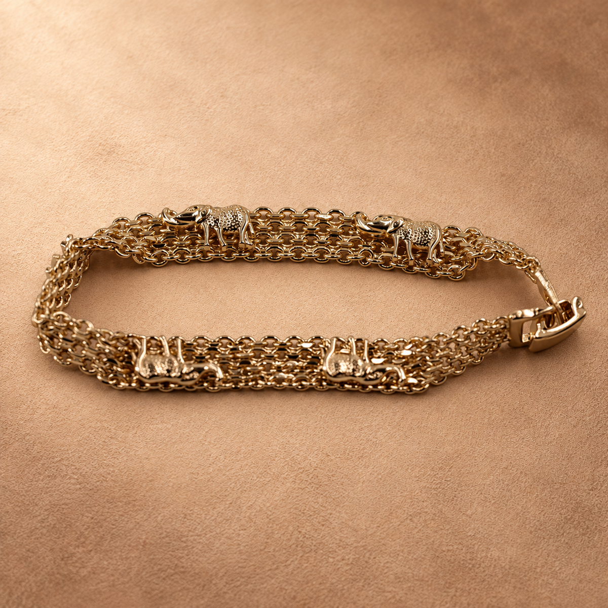 Angled close-up of the Nila elephant chain bracelet with its clasp closed, showing the raised elephant details and layered gold-plated links.