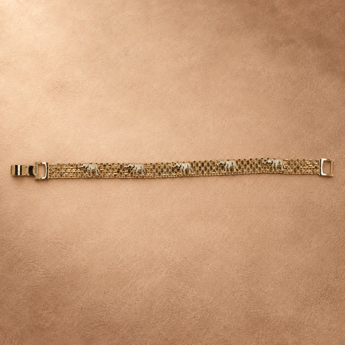 Full-length view of the Nila 14K gold-plated bracelet laid straight, with textured elephants along parallel chain rows and the clasp open.
