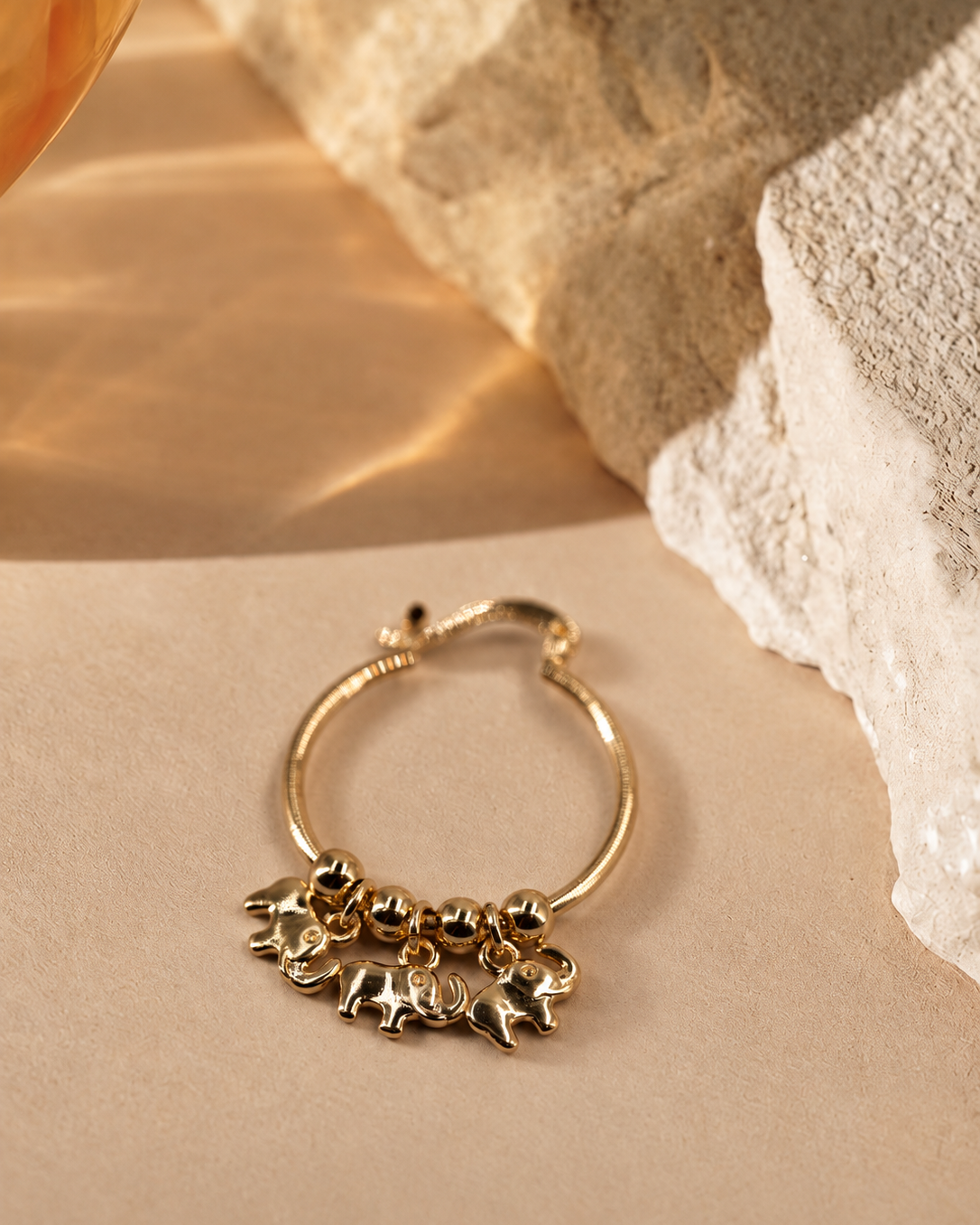 Close angled view of Nila elephant charm hoop earring, highlighting the elephant shapes and polished round beads.