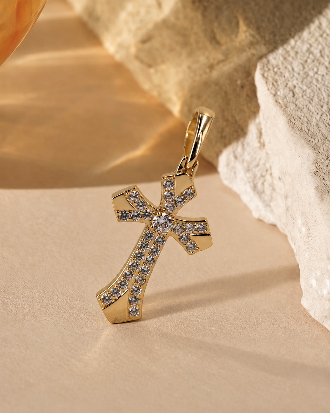 Seraphine cross pendant standing at an angle, showing flared ends, polished gold-plated panels and an elongated bail.