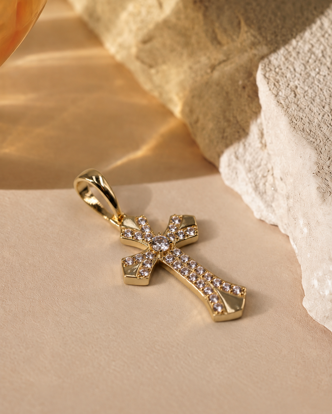 Low angled view of Seraphine cross pendant, highlighting the raised round center accent, curved detailing and polished edges.