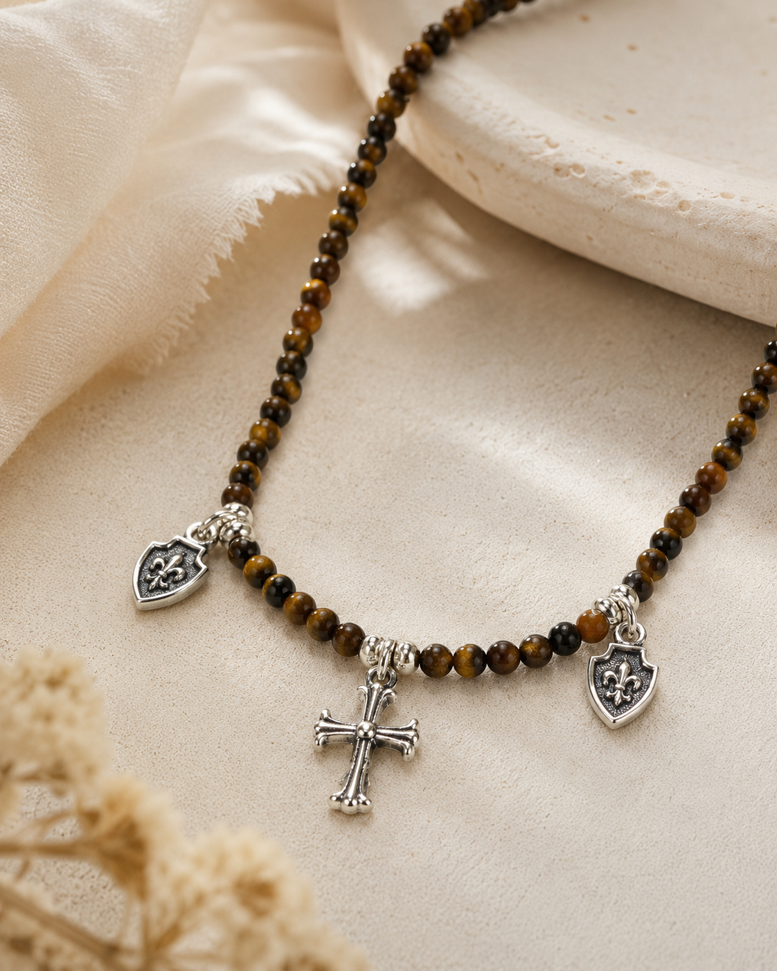 Close-up of tiger’s eye beads, sterling silver cross charm, and shield charms in Tiger’s Eye Cross Charm Beaded Necklace