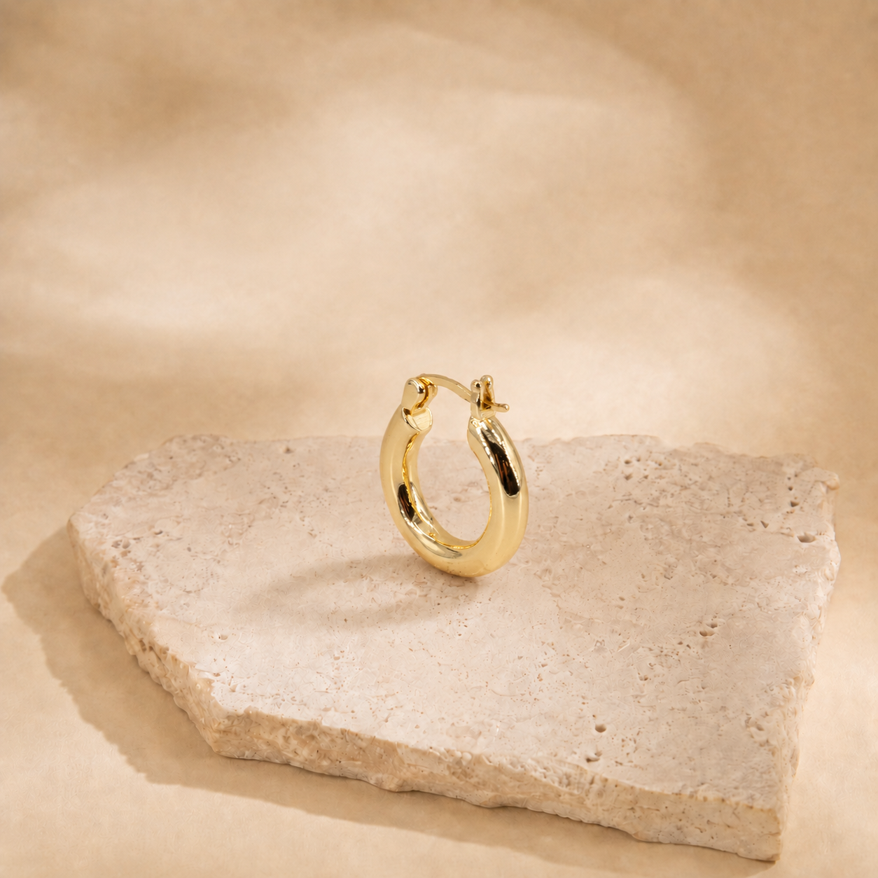 Alba classic hoop earring at an angle, showing the curved polished surface and hinged post fastening.