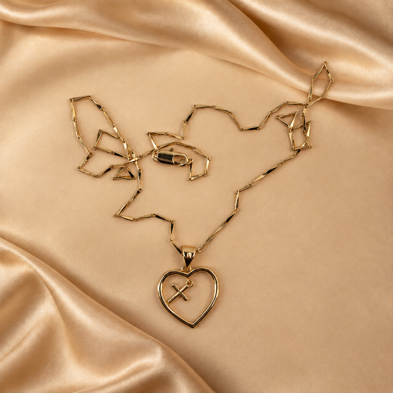 Front detail of the Amara open-heart pendant with a small hanging cross, alongside its 14K gold-plated chain and lobster clasp.