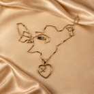 Front detail of the Amara open-heart pendant with a small hanging cross, alongside its 14K gold-plated chain and lobster clasp.