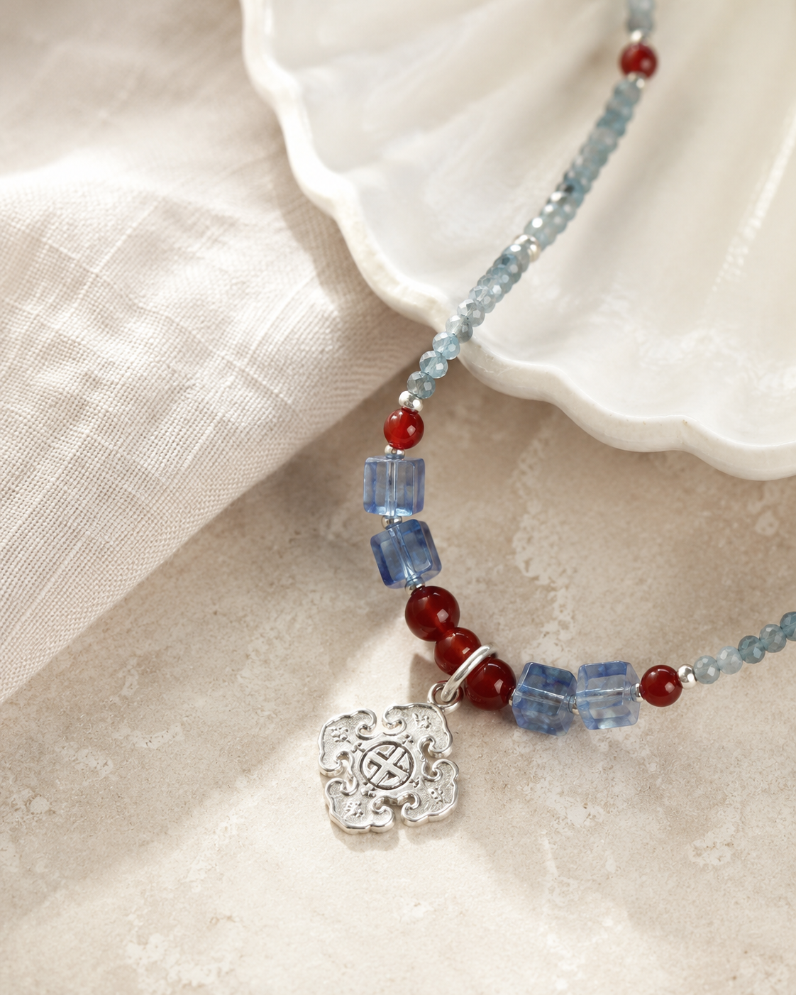 Close-up of sky blue quartz beads, red accents, sterling silver spacer beads, and sterling silver pendant in Azure Sky Blue Quartz Pendant Necklace