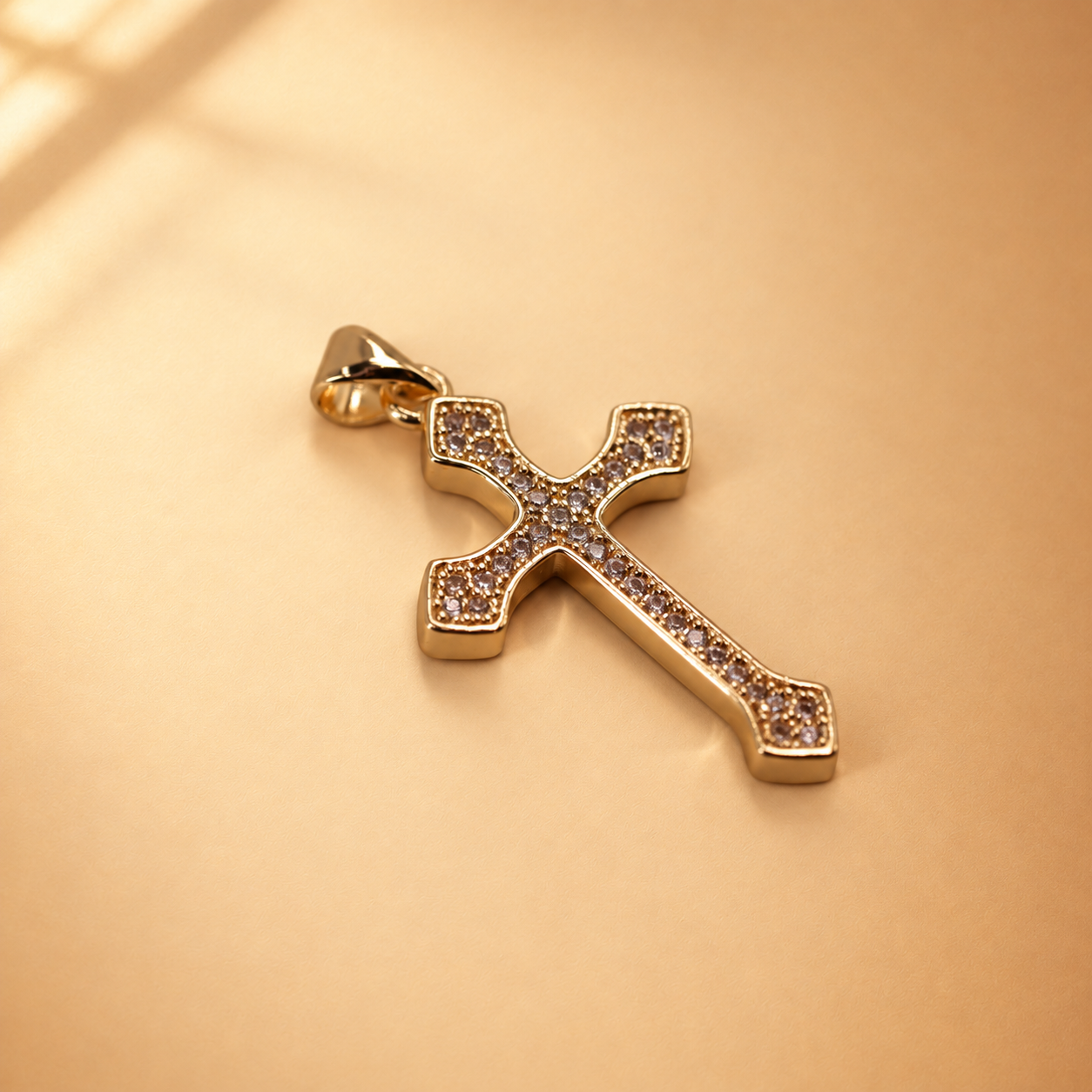 Low angled view of Clara cross pendant showing the polished gold-plated edge and clear accents across the front.