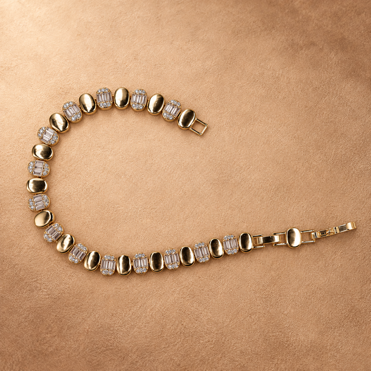Dalia oval link bracelet laid in an open curve, showing the clasp, polished gold finish and clear rectangular accents.