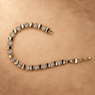 Dalia oval link bracelet laid in an open curve, showing the clasp, polished gold finish and clear rectangular accents.
