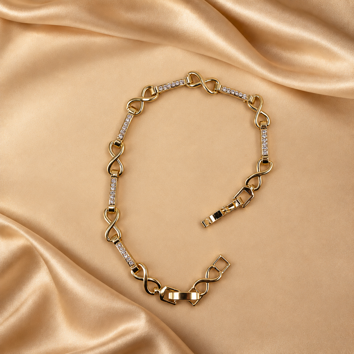 Evera 14K gold-plated steel bracelet laid open, showing infinity-shaped links alternating with bars of clear accents.