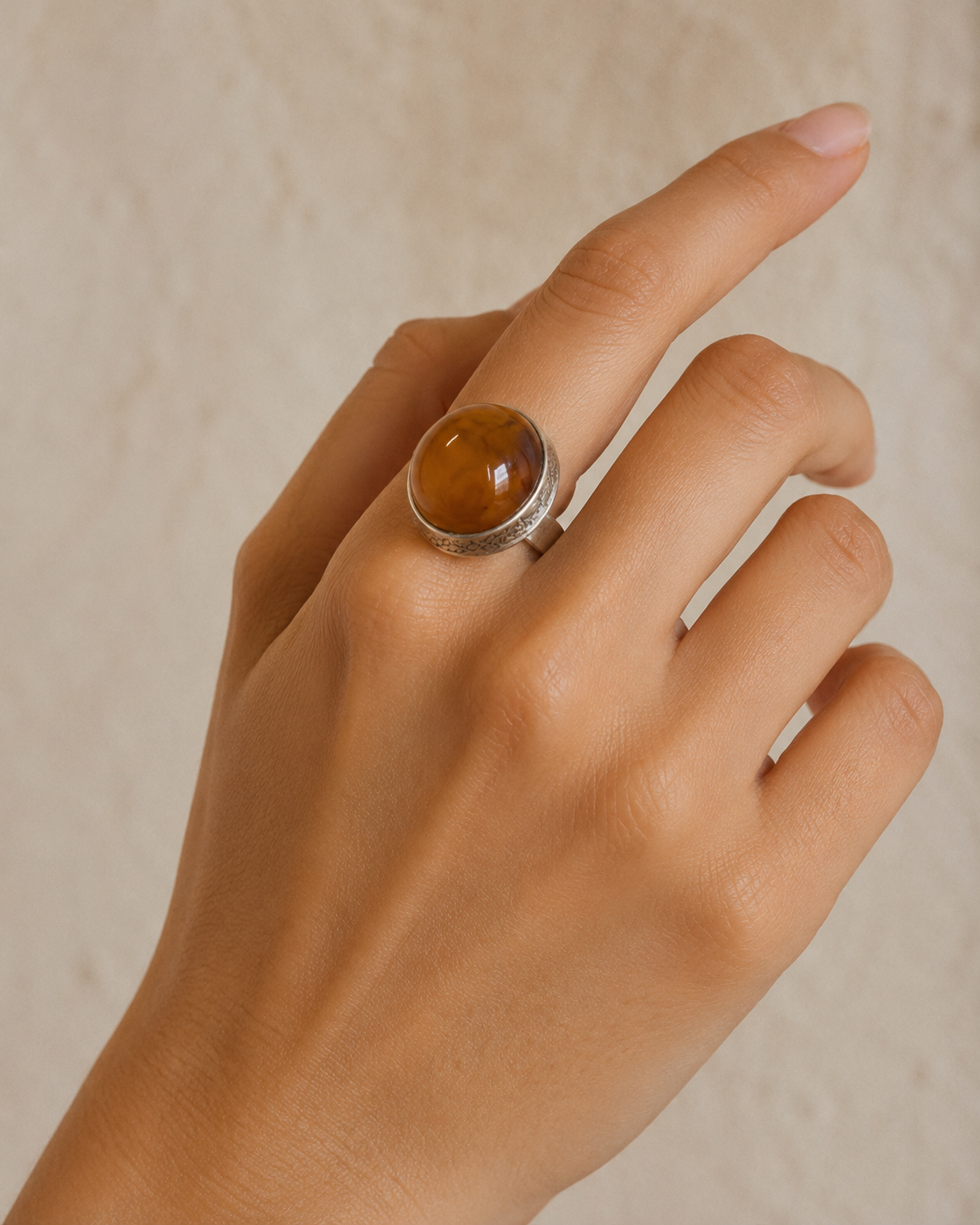 Close-up of polished golden-brown amber and sculptural sterling silver setting in Golden Amber Sterling Silver Adjustable Ring