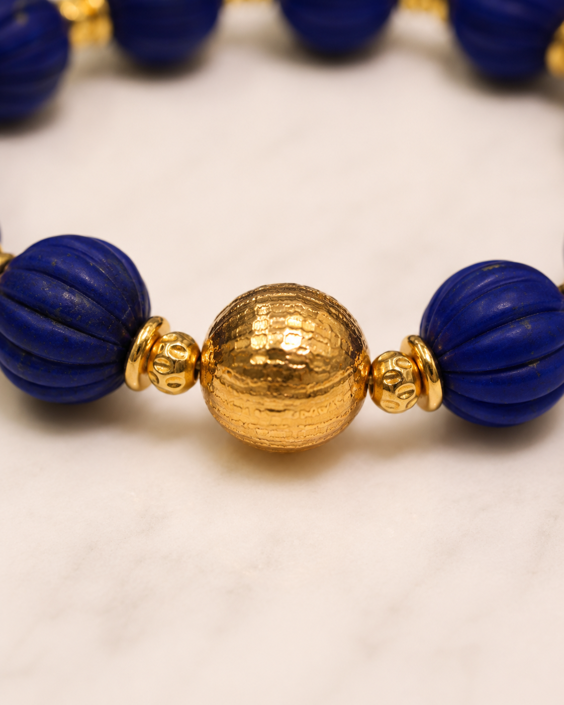 Close-up of carved lapis lazuli beads and gold-plated sterling silver detail in Lapis Lazuli Gold Beaded Statement Bracelet