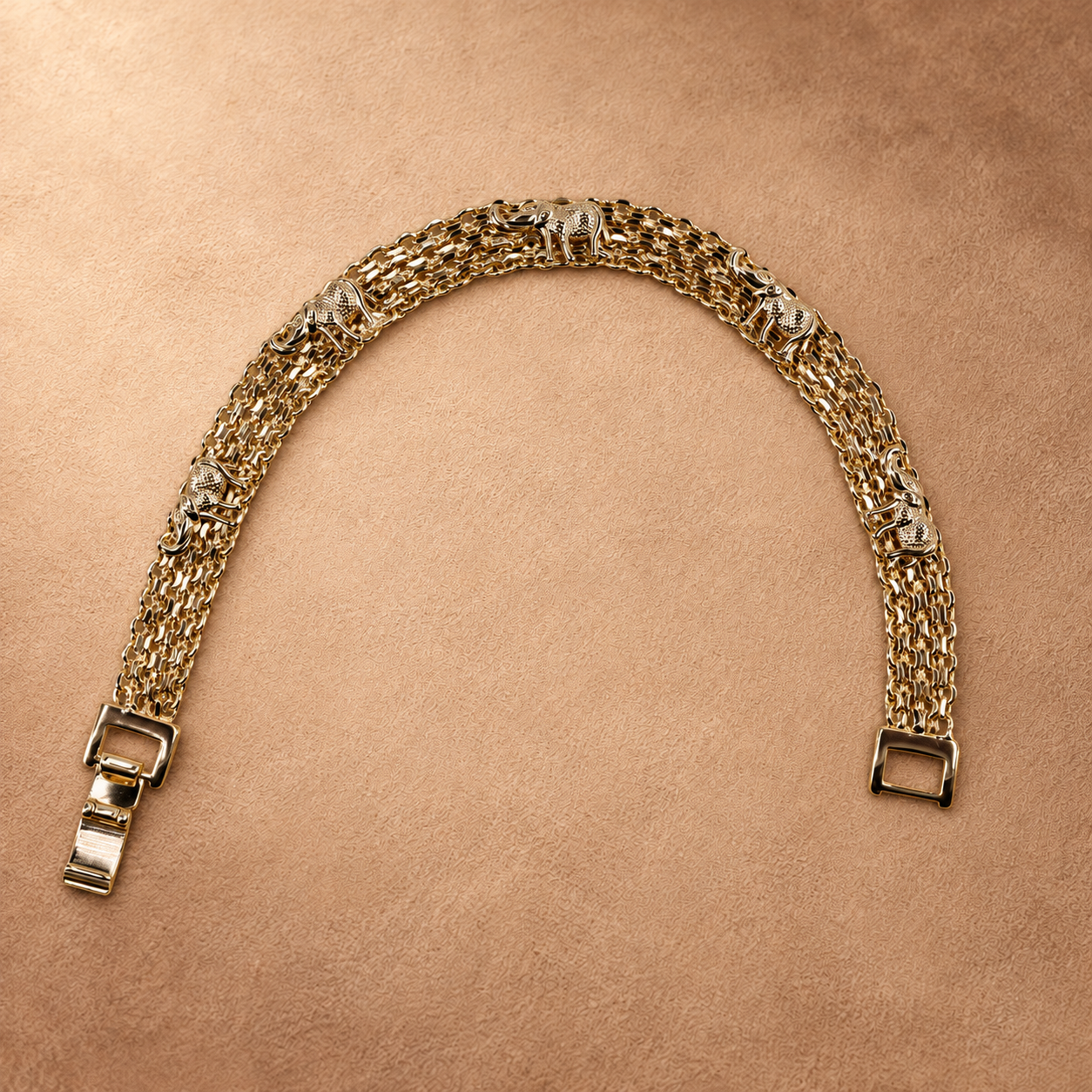 Nila 14K gold-plated elephant bracelet arranged in an open curve, showing textured elephant motifs, multiple chain rows and a fold-over clasp.