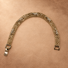 Nila 14K gold-plated elephant bracelet arranged in an open curve, showing textured elephant motifs, multiple chain rows and a fold-over clasp.