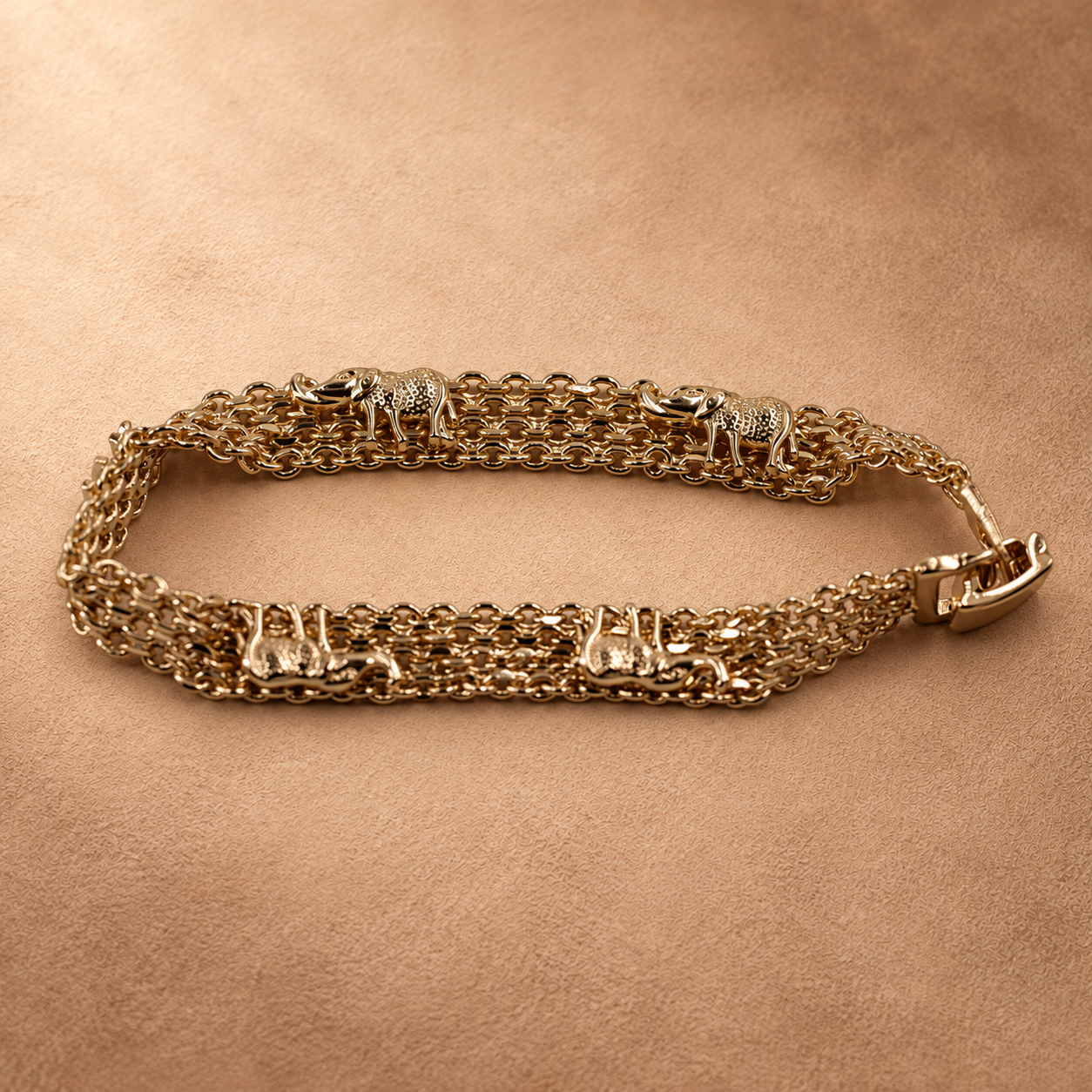 Angled close-up of the Nila elephant chain bracelet with its clasp closed, showing the raised elephant details and layered gold-plated links.