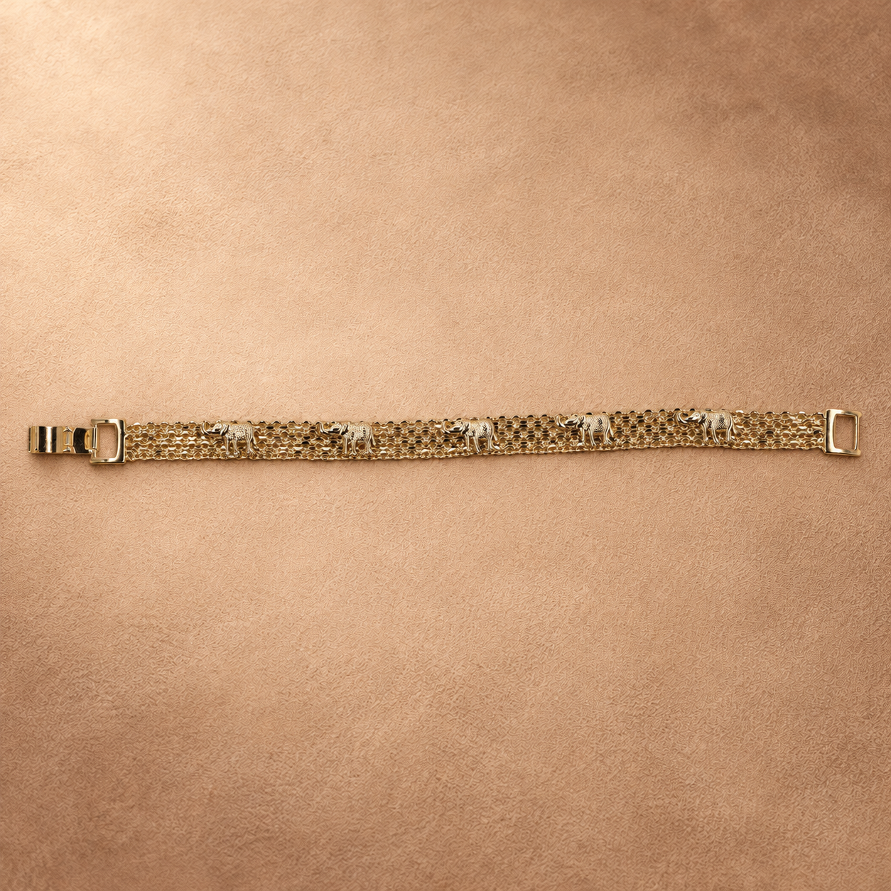 Full-length view of the Nila 14K gold-plated bracelet laid straight, with textured elephants along parallel chain rows and the clasp open.