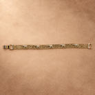 Full-length view of the Nila 14K gold-plated bracelet laid straight, with textured elephants along parallel chain rows and the clasp open.