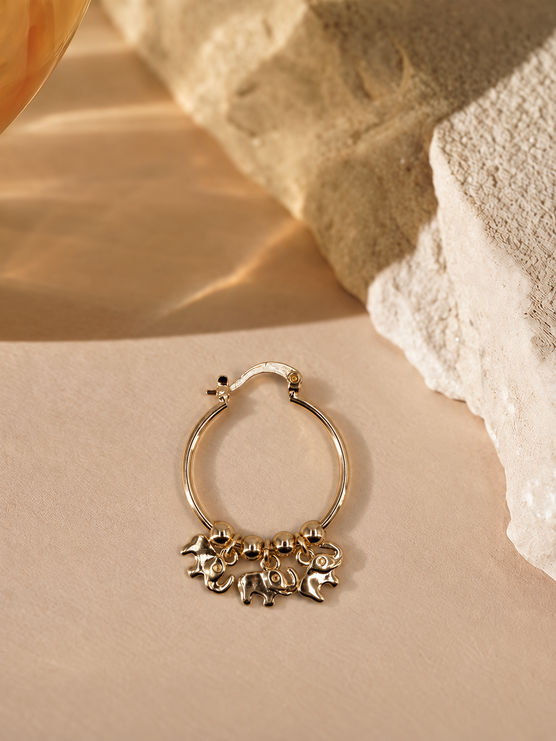 Nila 14K gold-plated steel hoop earring with three dangling elephant charms and polished round beads along the bottom.