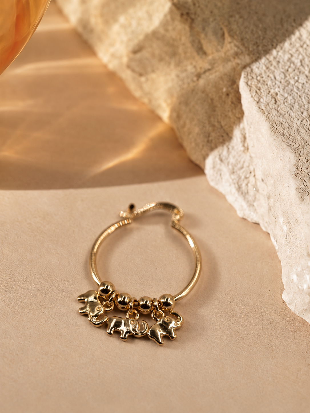 Close angled view of Nila elephant charm hoop earring, highlighting the elephant shapes and polished round beads.