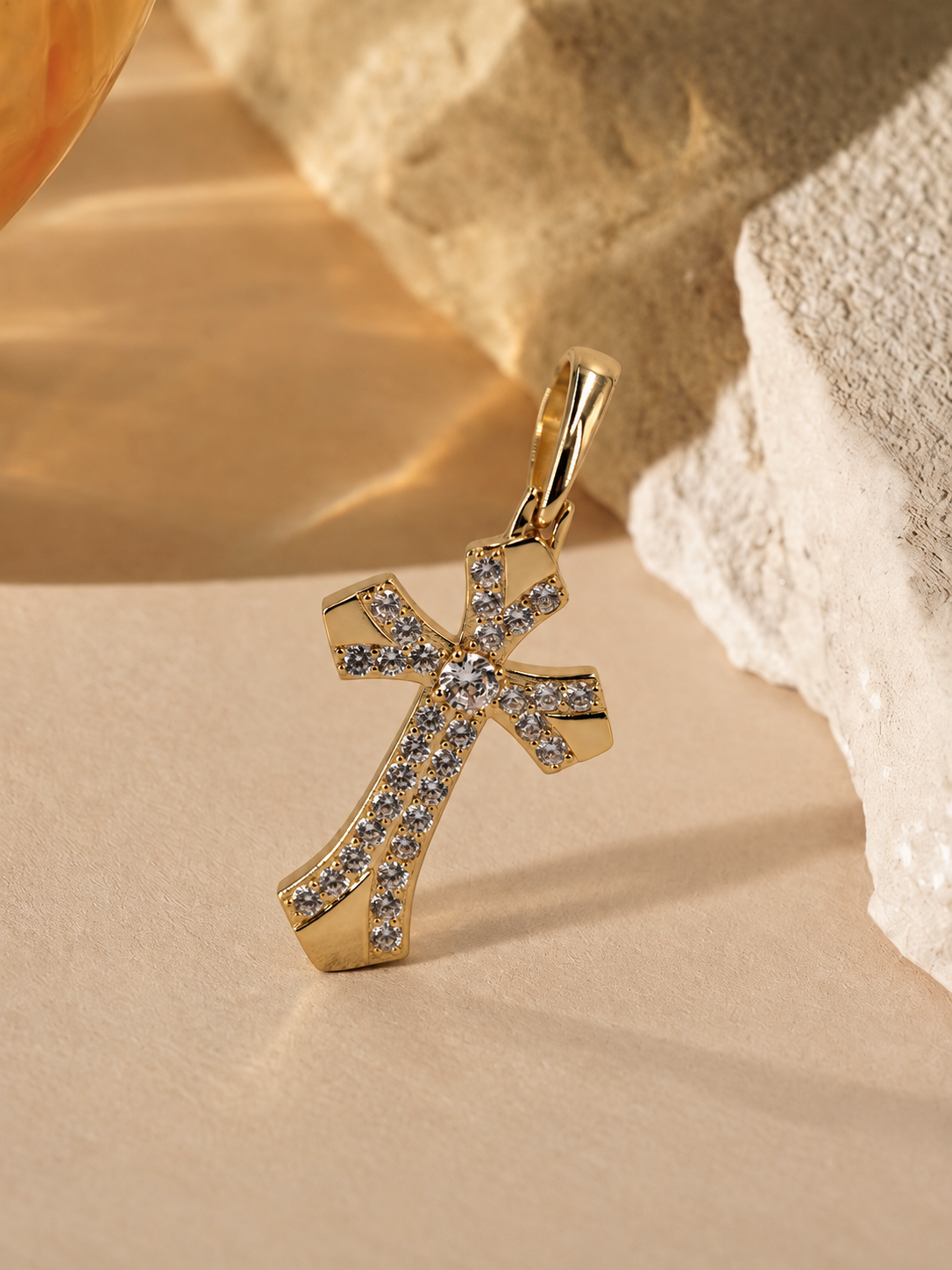Seraphine cross pendant standing at an angle, showing flared ends, polished gold-plated panels and an elongated bail.