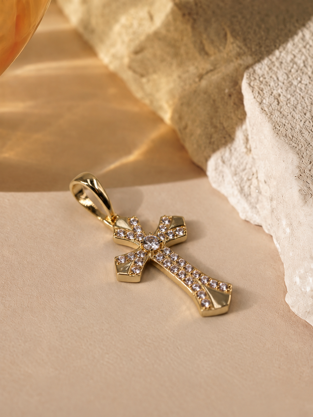 Low angled view of Seraphine cross pendant, highlighting the raised round center accent, curved detailing and polished edges.